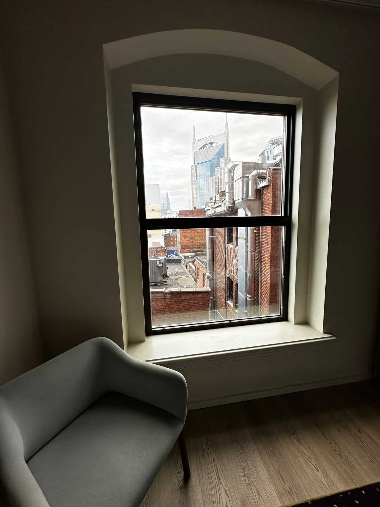 Gaze through the window to a stunning Nashville skyline, with a sleek gray chair perfectly positioned in the foreground.