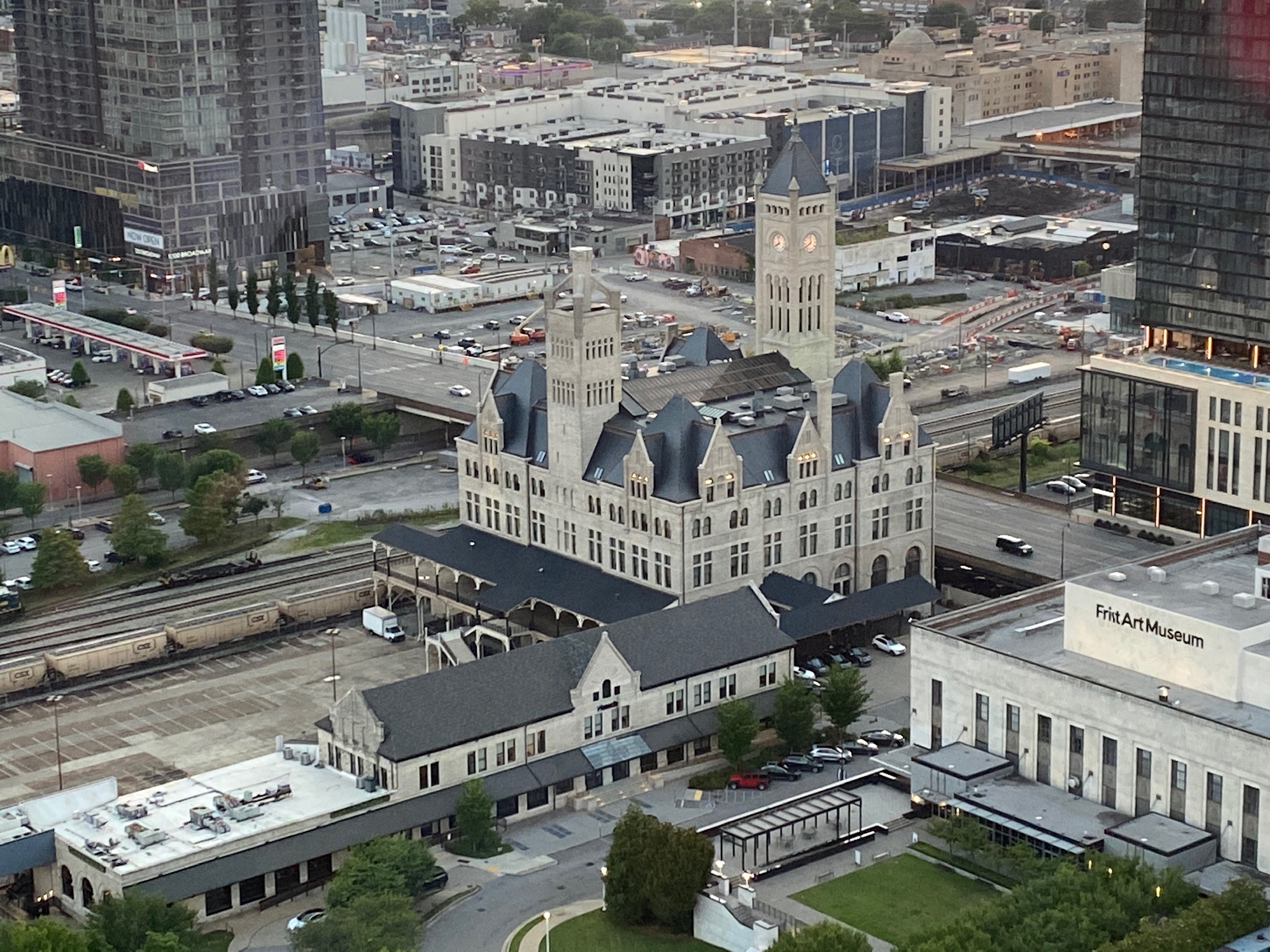 Aerial view of Union Station, an ornate historic building with a clock tower, surrounded by modern buildings, roads, and train tracks in downtown Nashville.