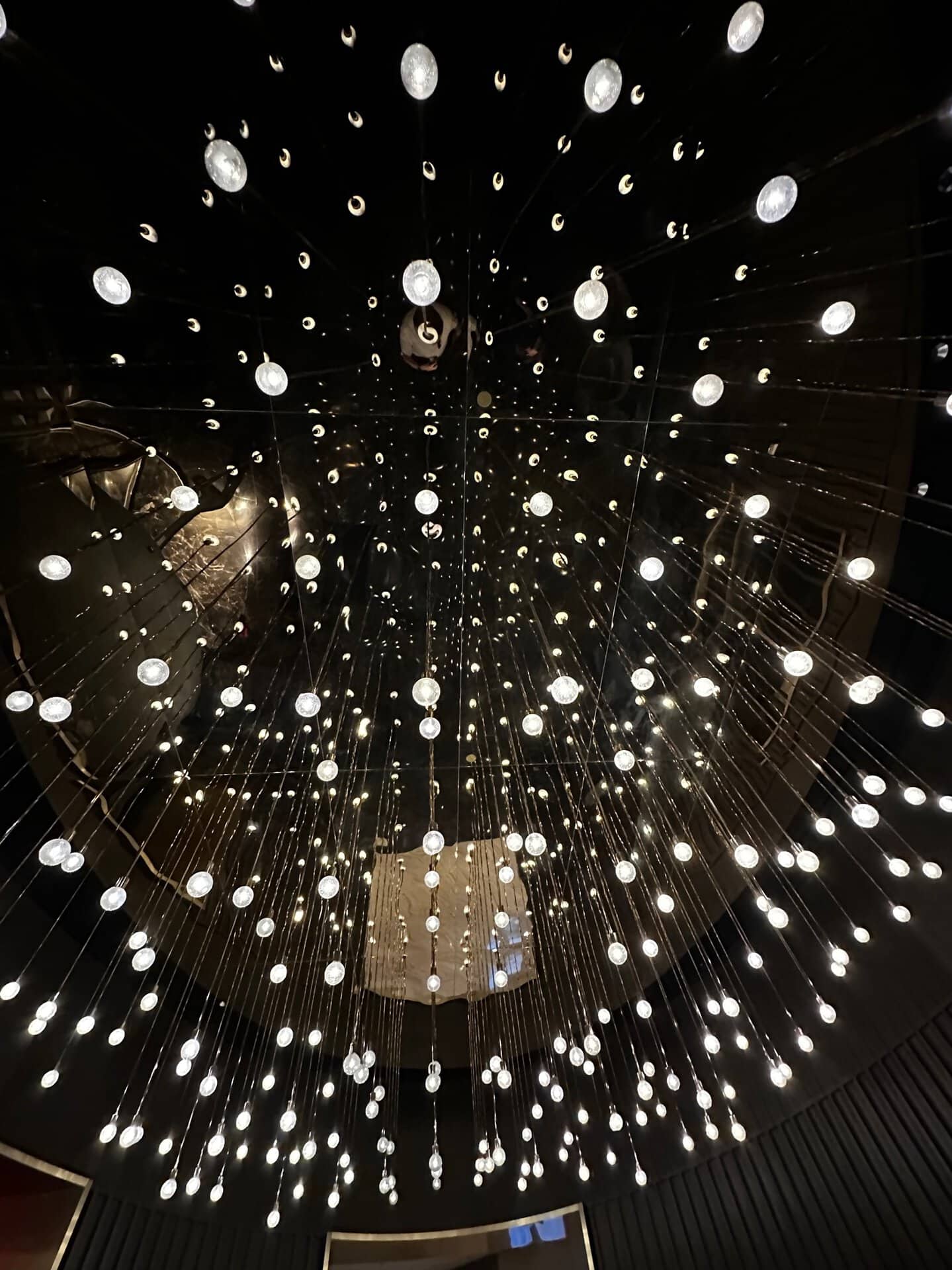 A view from below reveals numerous small lights suspended by wires, creating a mesmerizing circular pattern reminiscent of Nashville's vibrant nightlife.
