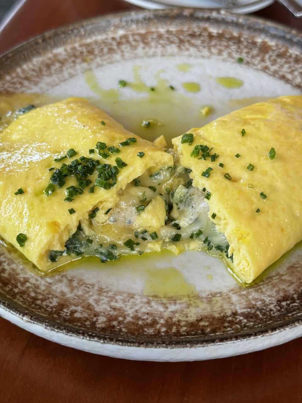 A folded omelette filled with spinach and cheese, split open on a brown-rimmed plate, garnished with chopped herbs—it's a taste reminiscent of Southern comfort that would be right at home in the heart of Nashville.