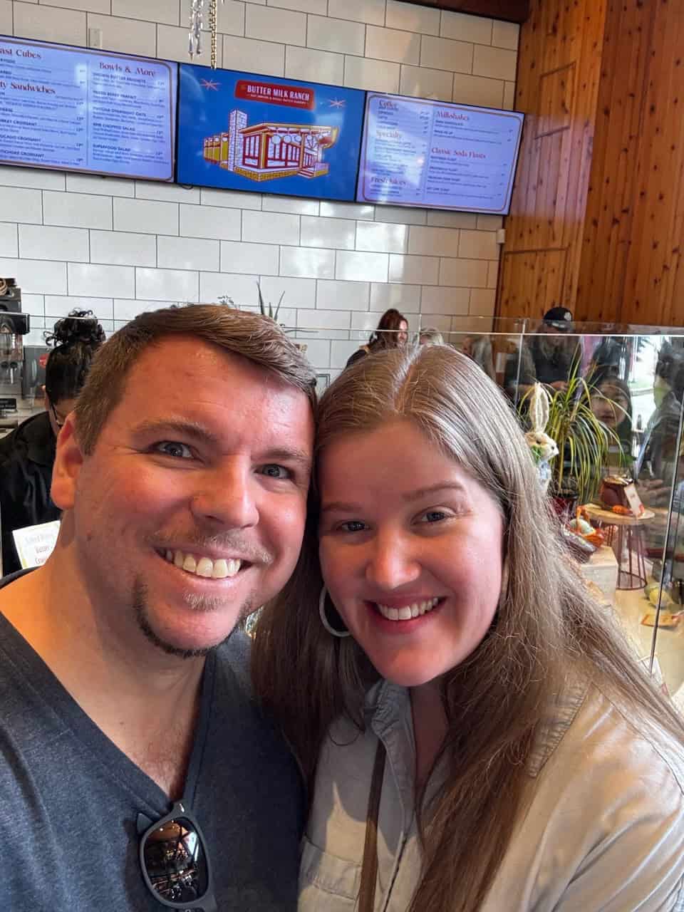 A man and a woman are smiling in a Nashville restaurant, with a menu display in the background.
