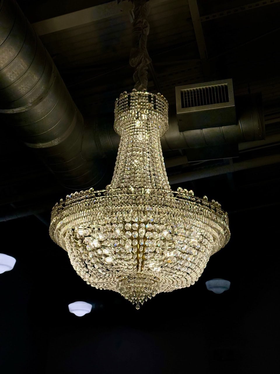 A large crystal chandelier elegantly hangs from the ceiling, casting a warm glow over Nashville's exposed pipes and vents.
