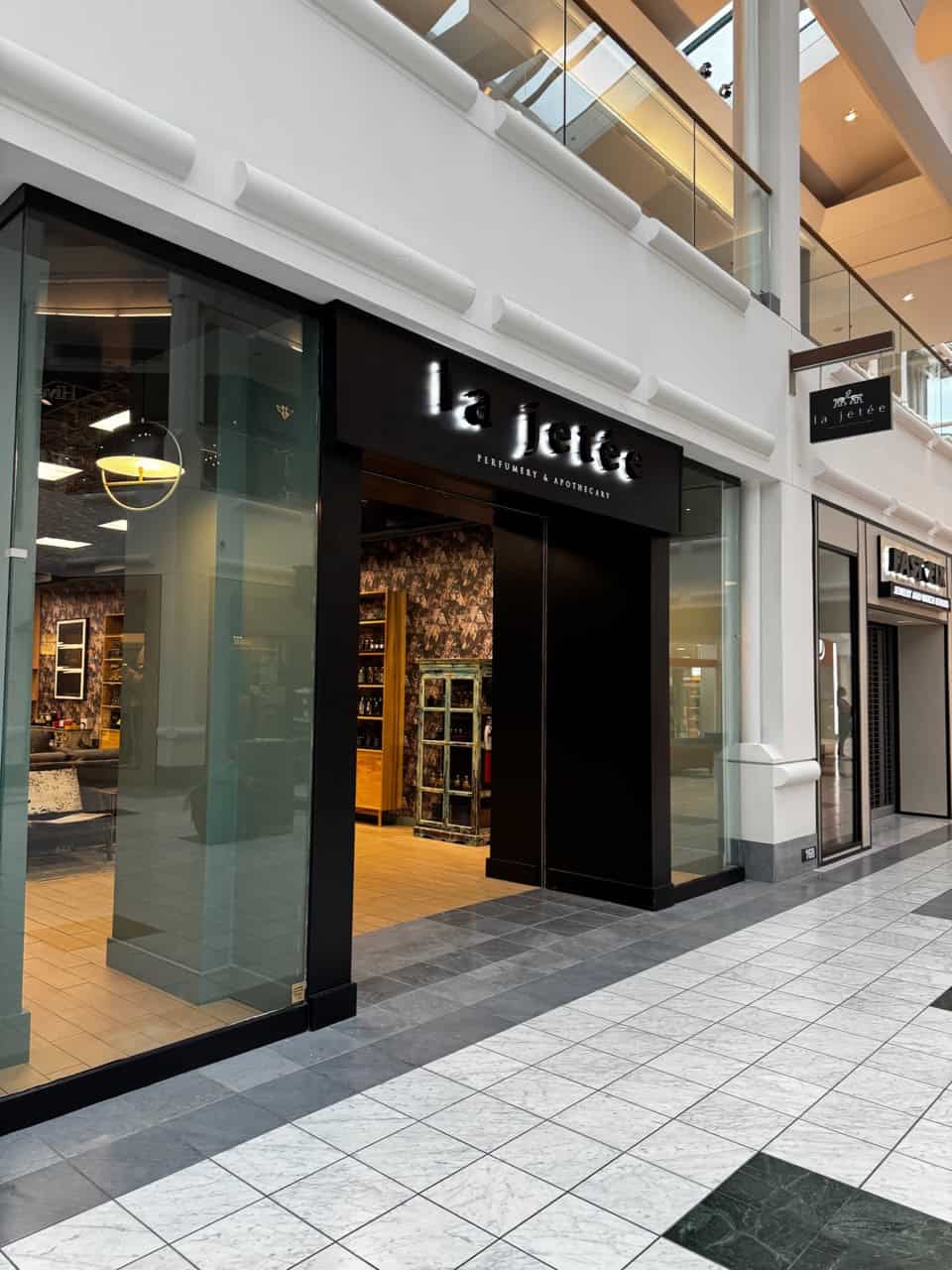 A modern storefront with a black sign reading "la jeté" stands in a Nashville mall. Inside, shelves and products are visible through large glass windows, inviting shoppers to explore.