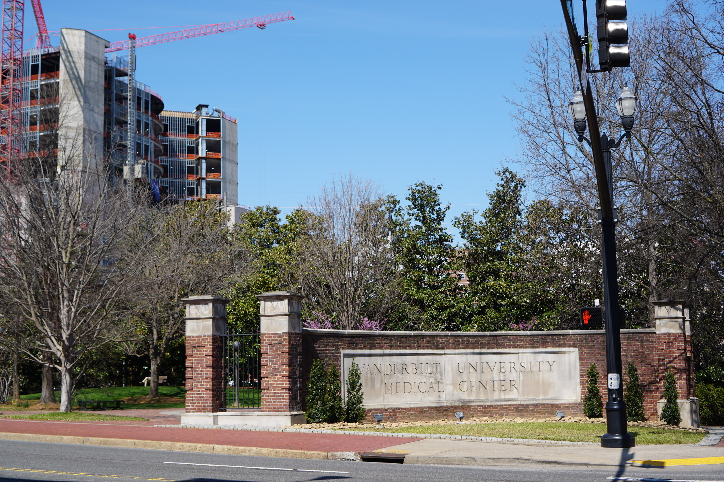 A brick and stone sign reads "Vanderbilt University Medical Center" near a sidewalk, with trees and a building under construction in the background.