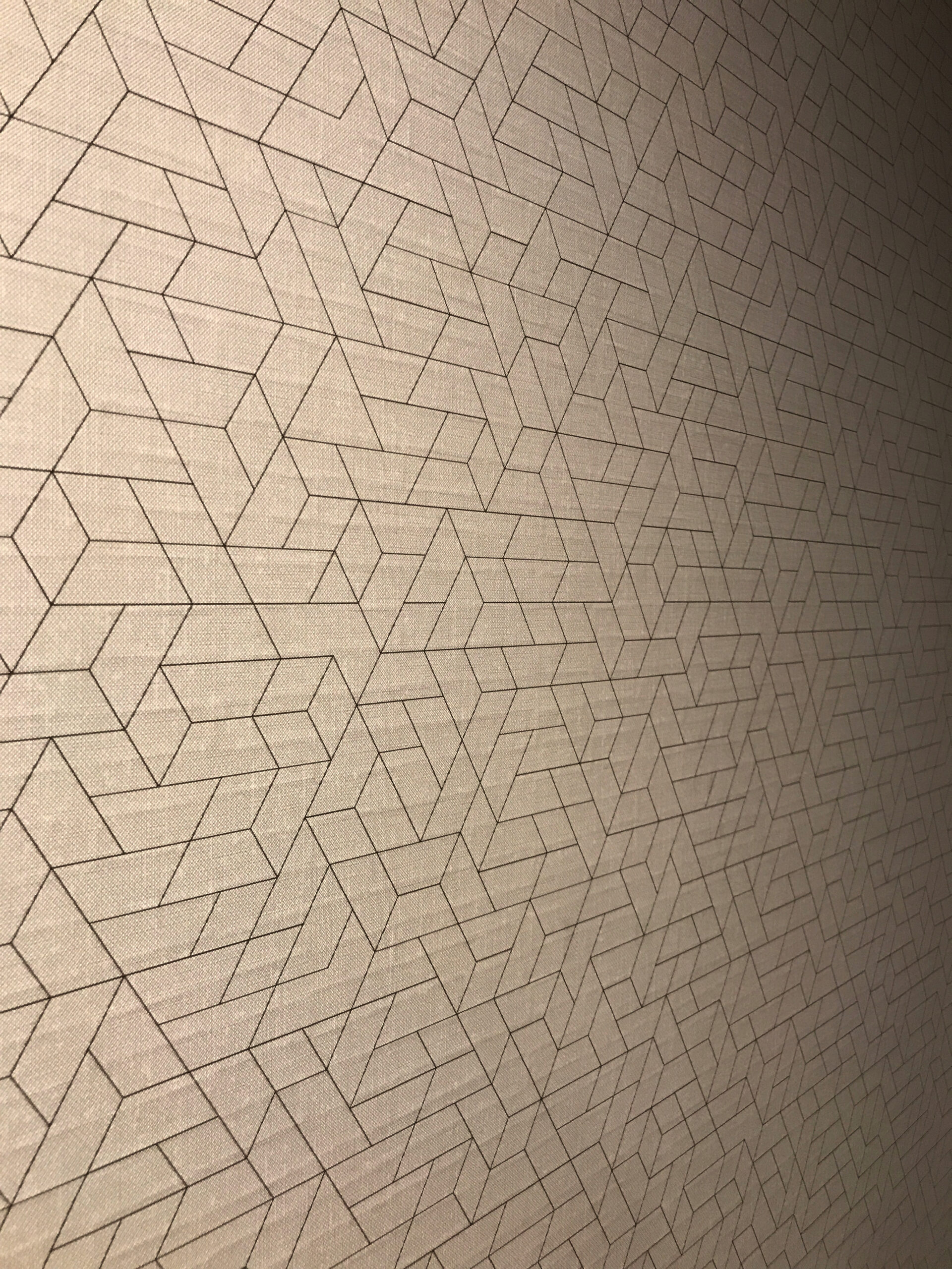 A beige wall featuring a geometric pattern of interlocking lines forming angular shapes.
