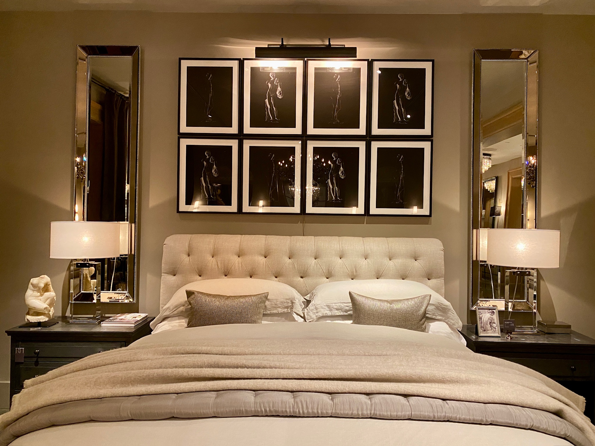 A neatly made bed with neutral bedding is flanked by matching lamps and nightstands; above the headboard, eight framed art prints evoke Nashville charm, arranged in two rows.