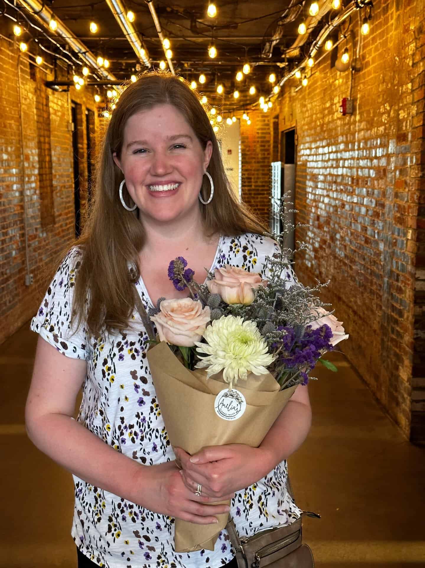 In a hallway aglow with string lights, a person beams with joy, holding a bouquet of flowers. It feels like a little piece of Nashville's charm captured in one delightful moment.