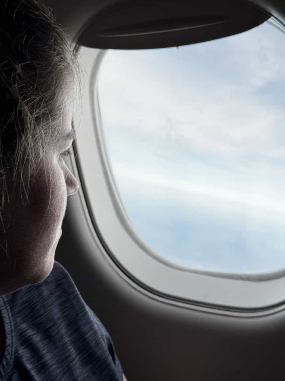 A person gazes out the airplane window, marveling at the clouds and sky, while anticipating their arrival in vibrant Nashville.