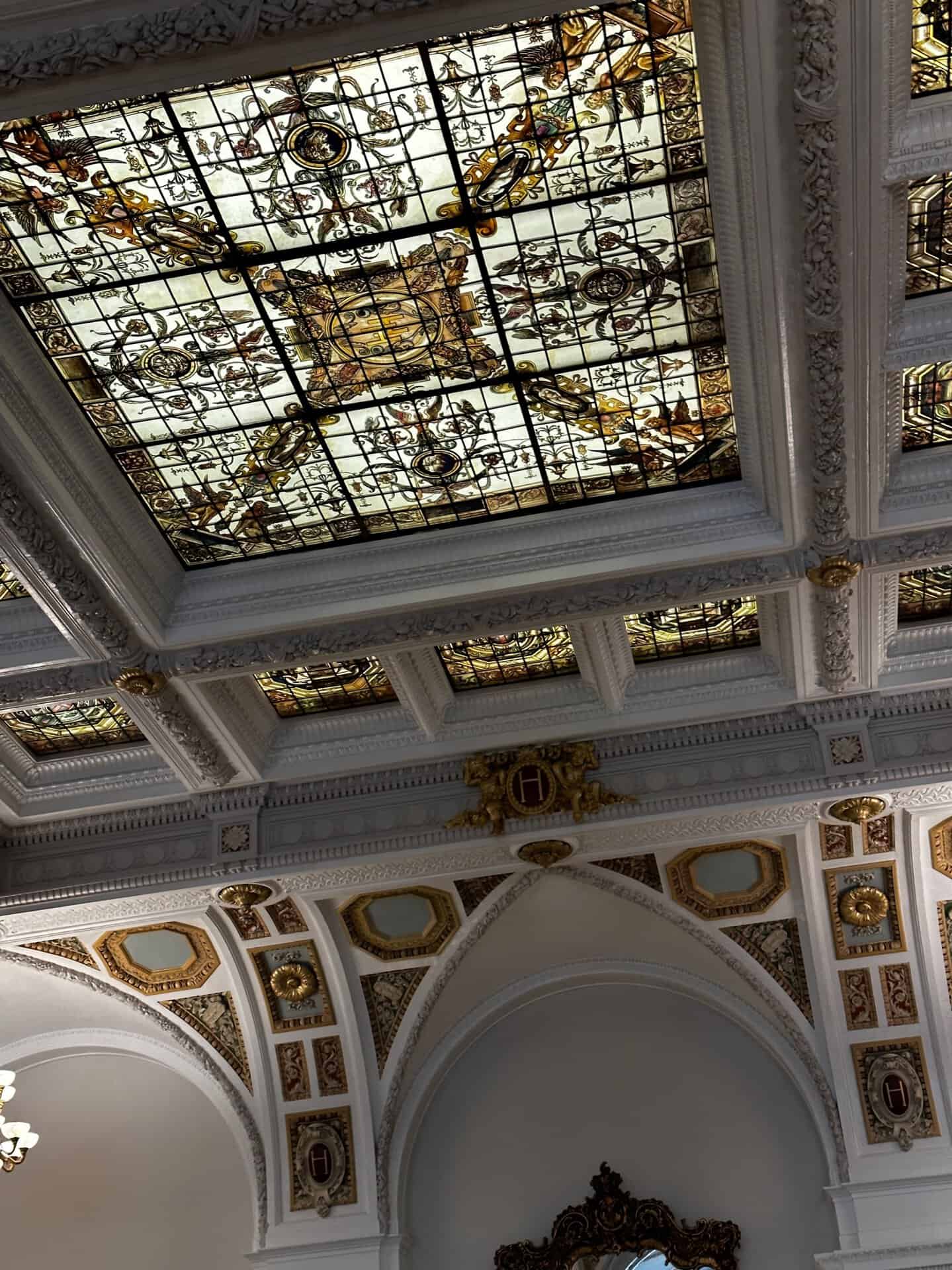 Nashville's historic building boasts a stunning stained glass ceiling with intricate patterns nestled within a white, ornately decorated coffered structure and archways.