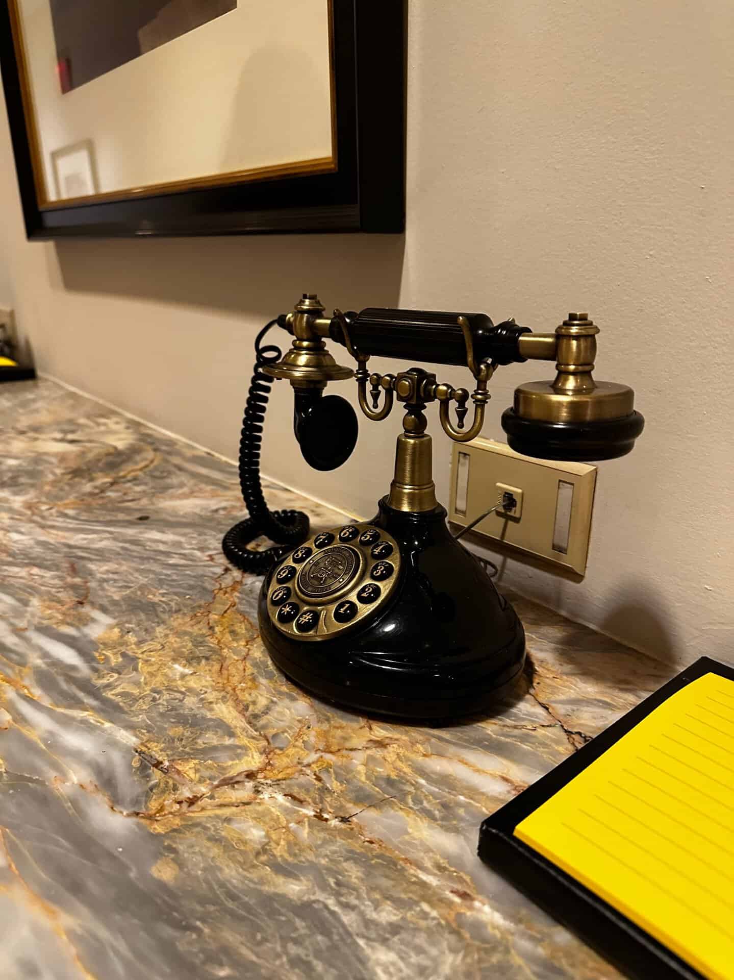 A vintage rotary telephone with brass accents sits on a marble surface next to a yellow notepad, evoking the charm of Nashville's timeless elegance.