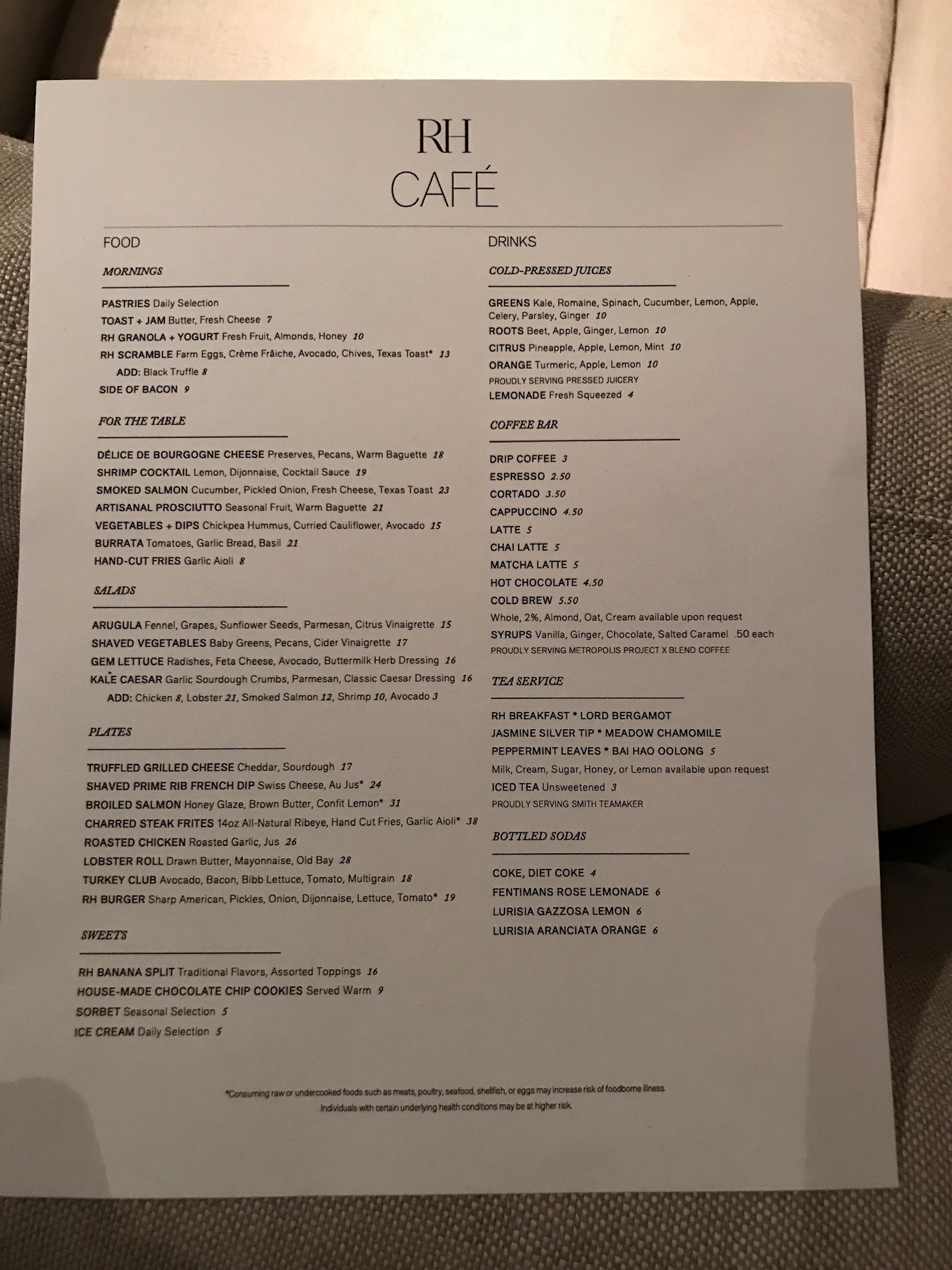 Menu for RH Café featuring sections for food and drinks, including breakfast items, cheese boards, salads, sandwiches, coffee, tea, fresh juices, and desserts, printed on a cream background.