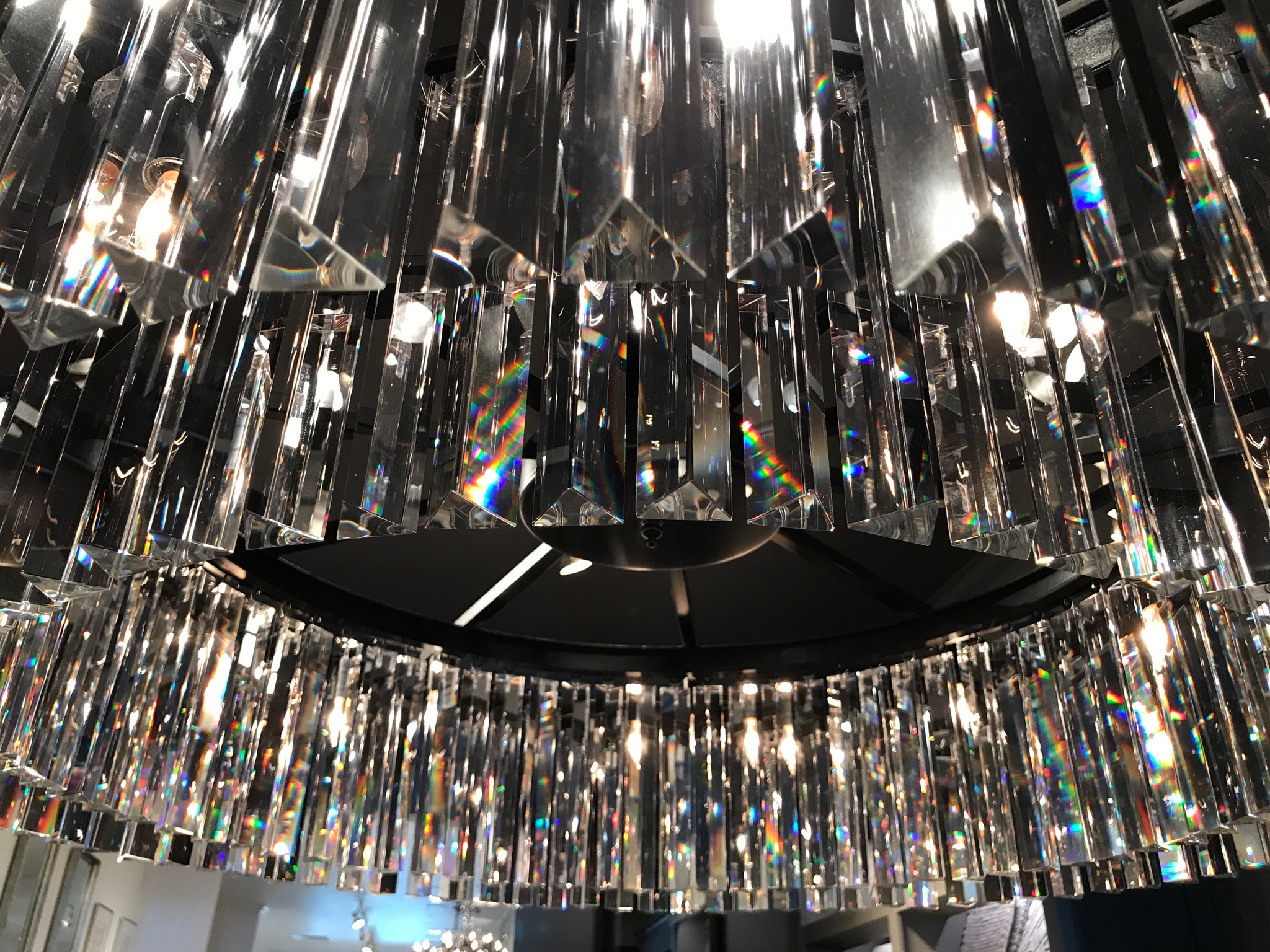 Close-up view of a chandelier with multiple clear, rectangular crystal prisms reflecting light and creating rainbow patterns.