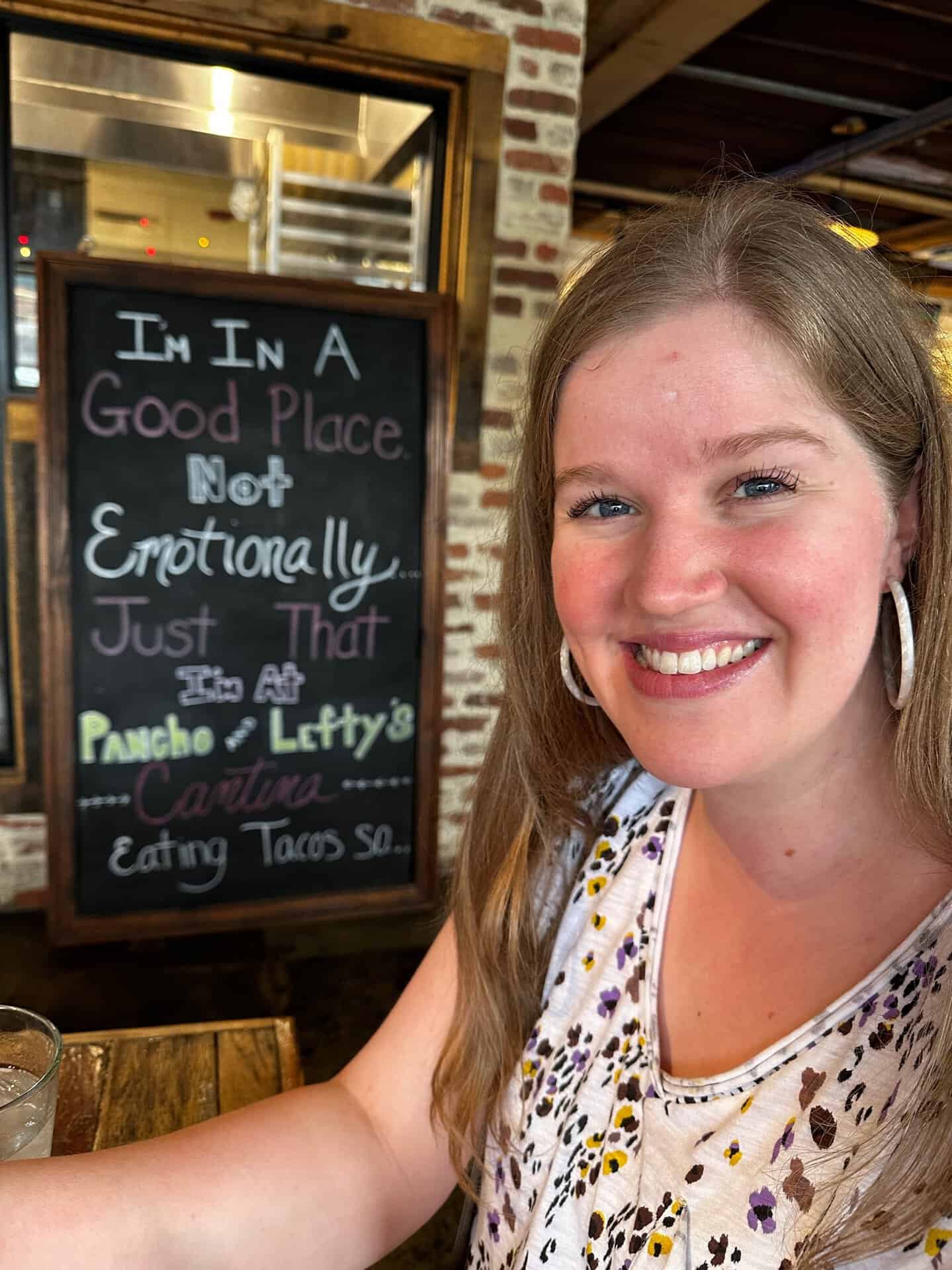 A smiling person stands before a chalkboard sign declaring, "I’m in a good place. Not emotionally. Just that I’m at Pancho & Lefty’s Cantina in Nashville, enjoying some tacos.