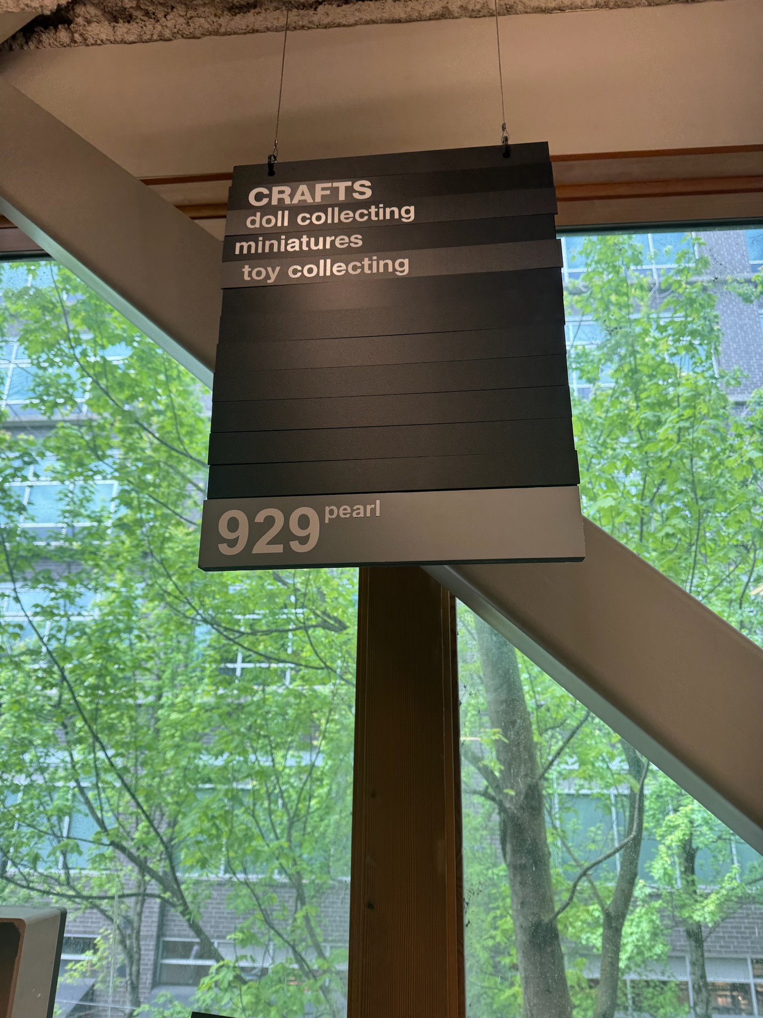 A hanging sign labeled "CRAFTS" lists "doll collecting," "miniatures," and "toy collecting," with "929 pearl" at the bottom. A window with trees is in the background.