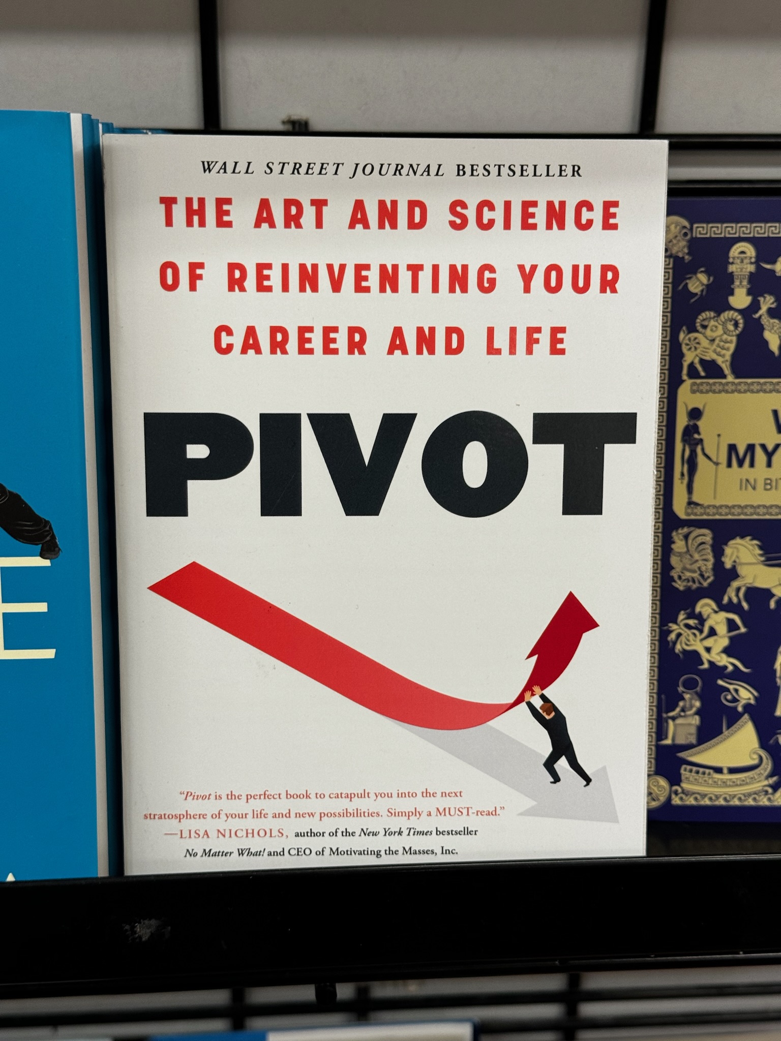 A book titled "PIVOT: The Art and Science of Reinventing Your Career and Life" by Lisa Nichols is displayed on a shelf, featuring an illustration of a person turning a large arrow.