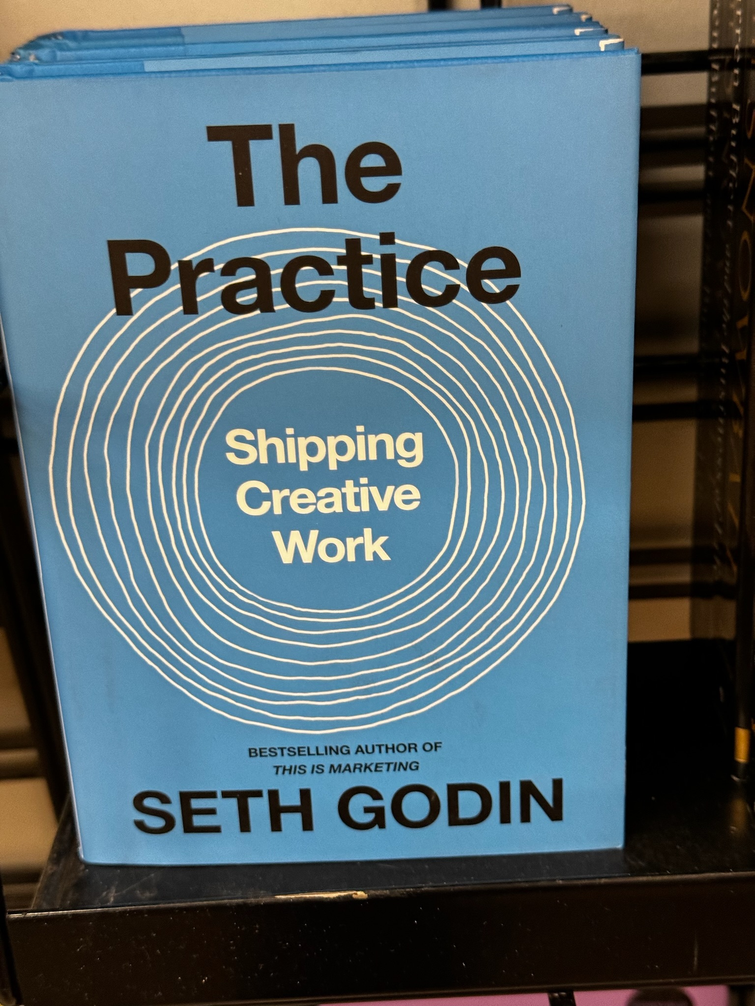 The cover of the book "The Practice: Shipping Creative Work" by Seth Godin, featuring concentric white circles on a blue background.