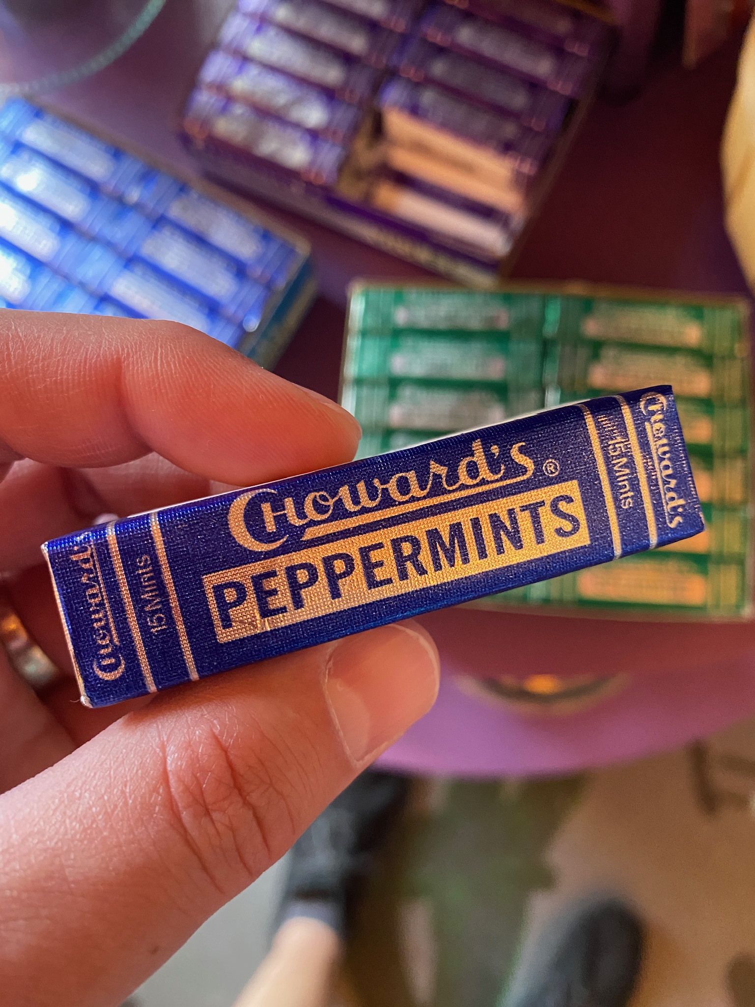 A hand holding a small blue box labeled "Howard's Peppermints" with other similar boxes in the background.