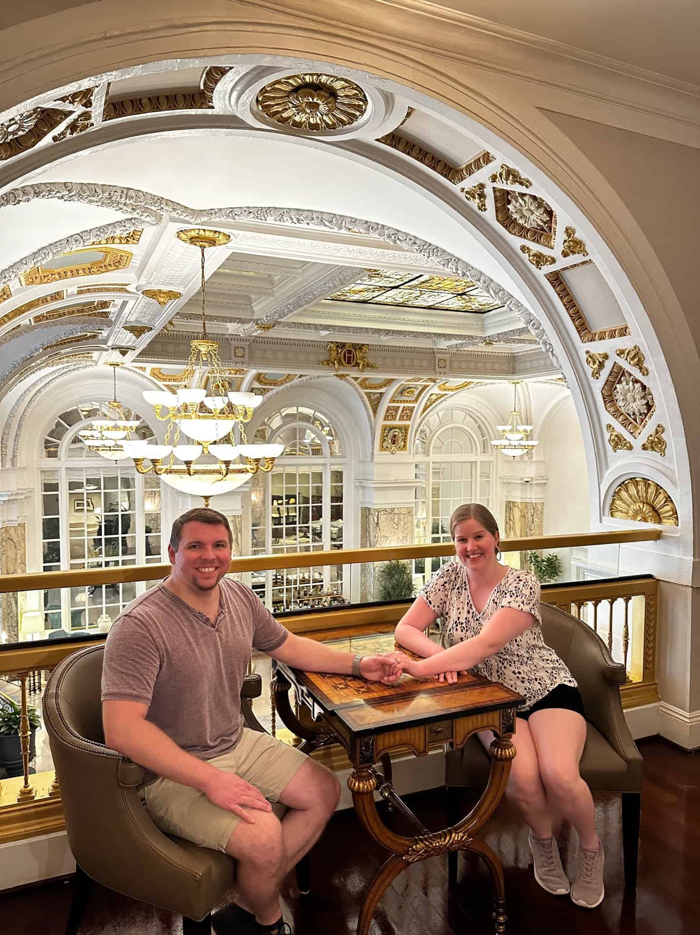 A man and woman sit at a small table in an ornate Nashville interior, surrounded by decorative arches and chandeliers.