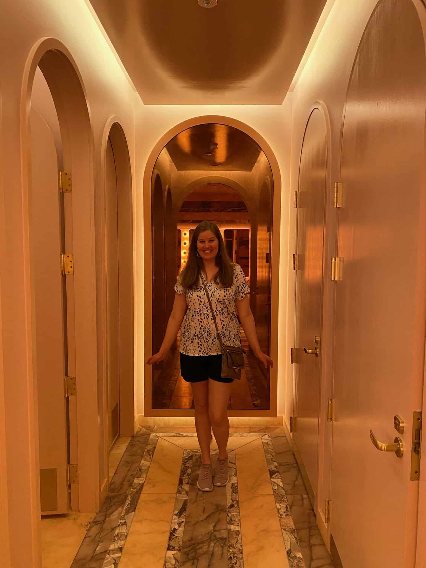 A person stands in a warmly lit hallway with arched doorways, a marble floor, and soft yellow lighting reminiscent of a Nashville evening.