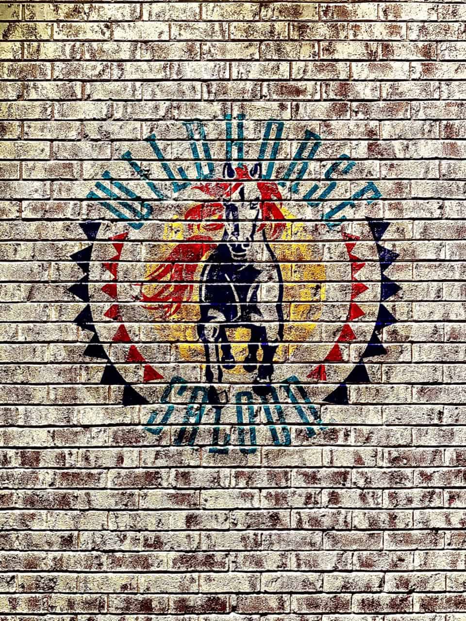 A mural of a horse with a red mane graces a brick wall in Nashville, surrounded by a circular pattern with text reading "Wild Horse Saloon.